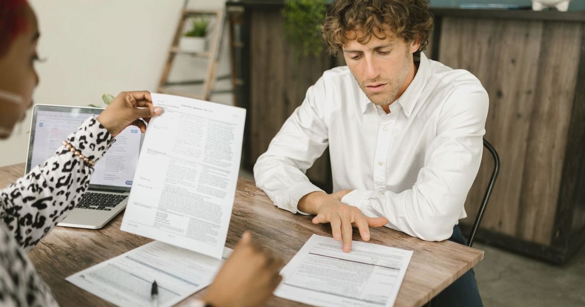 Two professionals reviewing documents in an office setting, focused on analytical tasks.