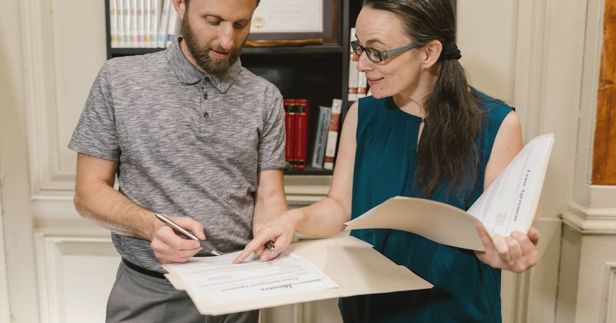 Two adults reviewing documents during a legal consultation in an office setting.