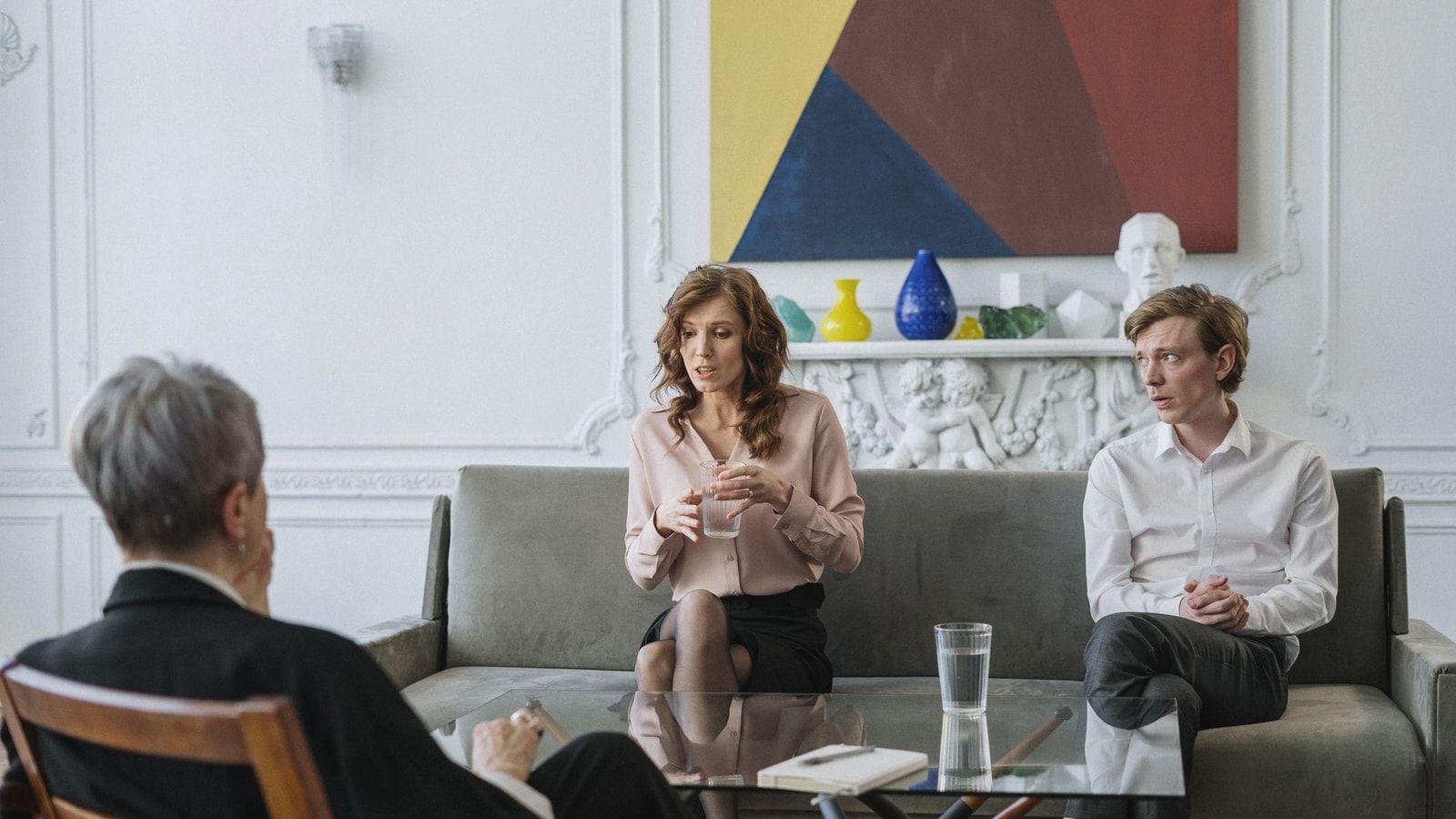 A couple conversing with a therapist in a chic, modern office setting.