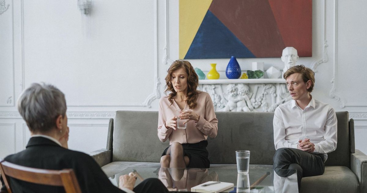A couple conversing with a therapist in a chic, modern office setting.