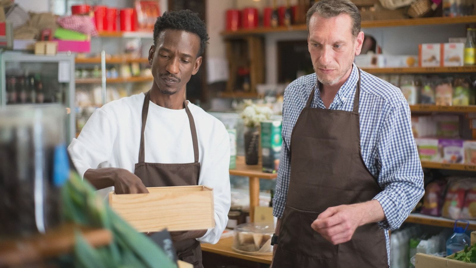 Two male employees organizing products in a cozy grocery store.