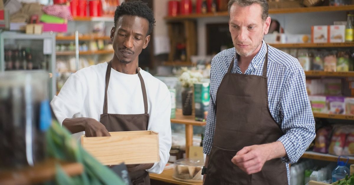 Two male employees organizing products in a cozy grocery store.