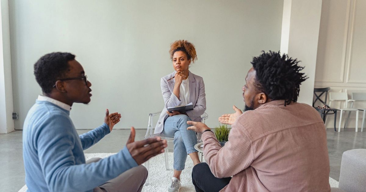 A therapy session featuring a diverse group discussing issues with a mental health professional.