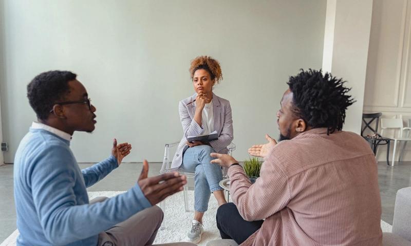 A therapy session featuring a diverse group discussing issues with a mental health professional.
