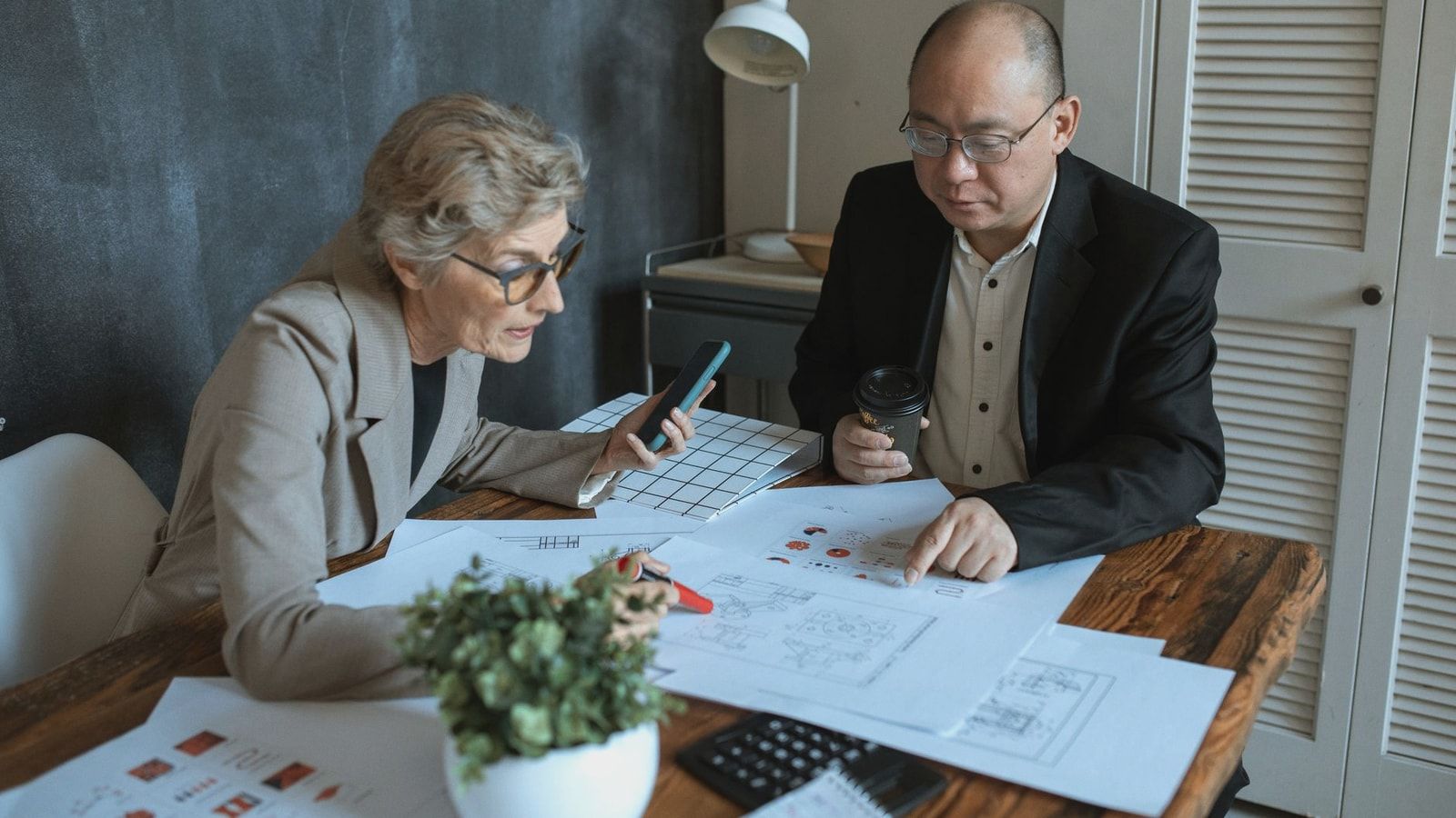Diverse team of professionals working on project plans at a desk. Collaborative business environment.