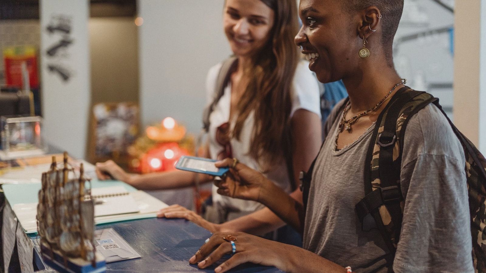 Two travelers check in at a hotel reception, smiling and engaging with the staff.