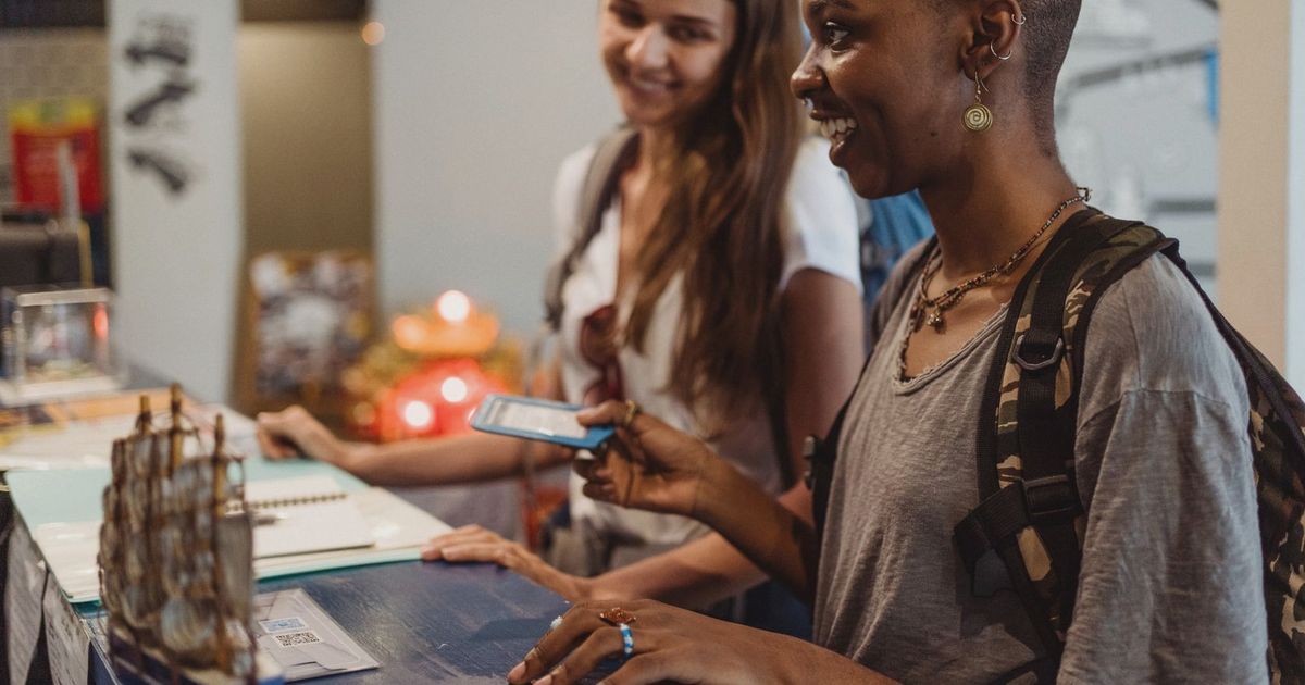 Two travelers check in at a hotel reception, smiling and engaging with the staff.