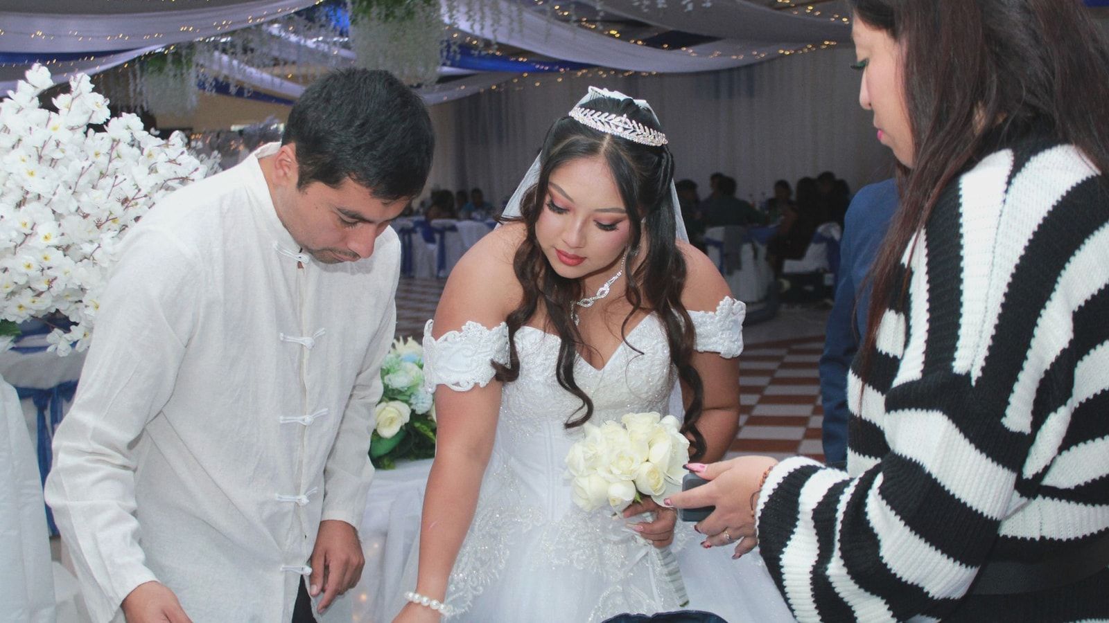 Bride signs a document at an elegant wedding ceremony surrounded by guests.