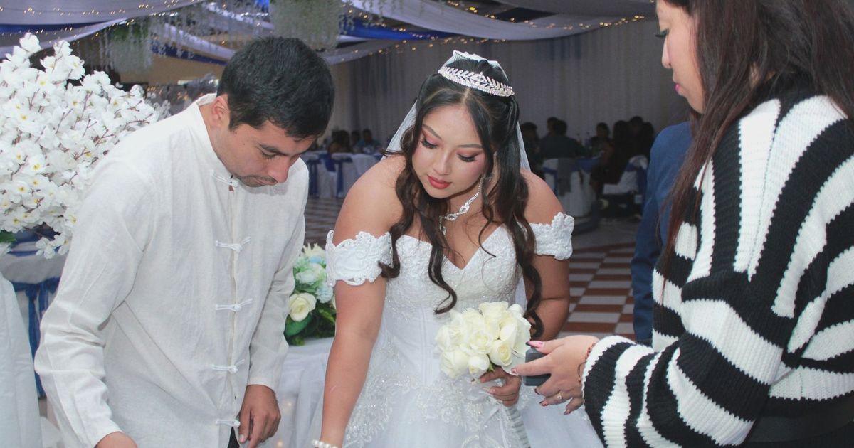 Bride signs a document at an elegant wedding ceremony surrounded by guests.