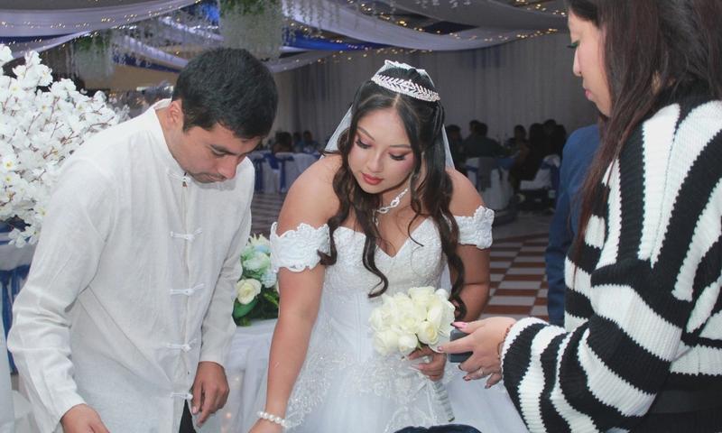 Bride signs a document at an elegant wedding ceremony surrounded by guests.