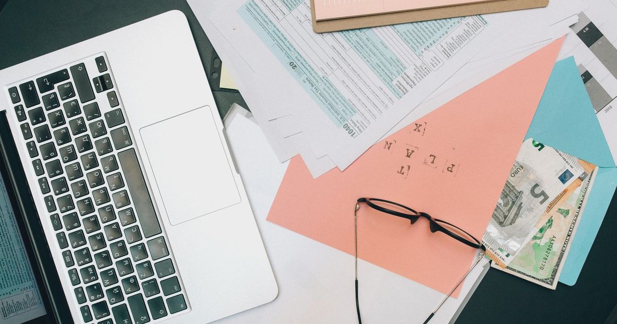 A tidy workspace featuring a laptop, documents, and eyeglasses for productivity.