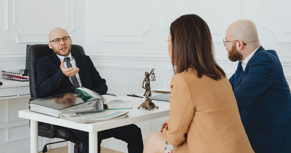 Three adults in a formal business meeting discussing legal matters in an office.