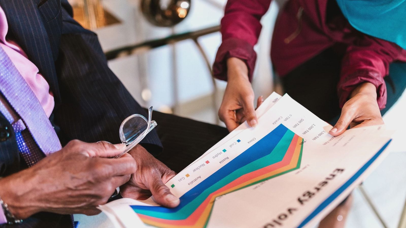 Two professionals reviewing detailed energy consumption charts in an office setting.