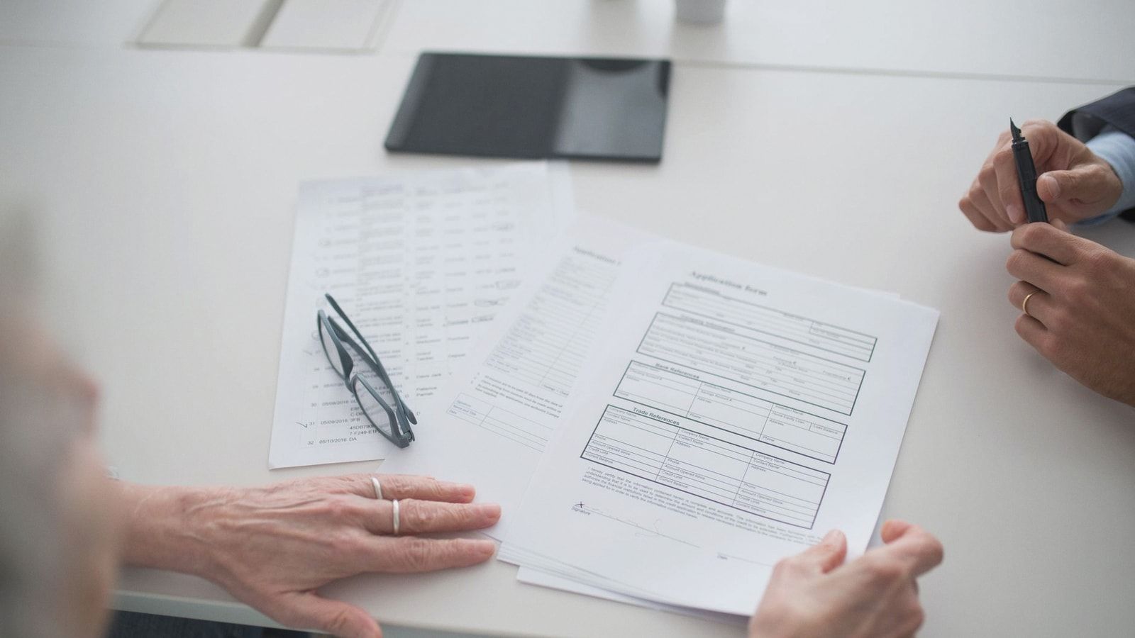 Close-up view of two individuals reviewing documents and forms in an office setting.