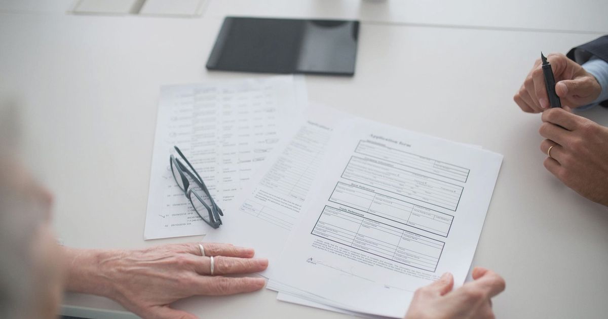 Close-up view of two individuals reviewing documents and forms in an office setting.