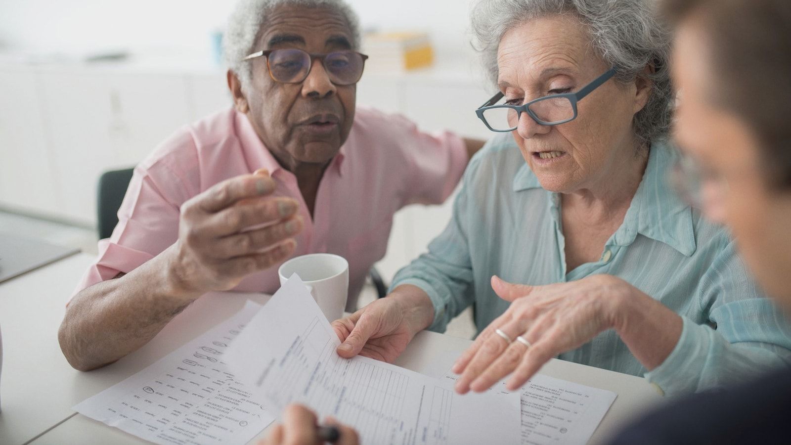Elderly couple discussing financial documents with a consultant in an office setting.