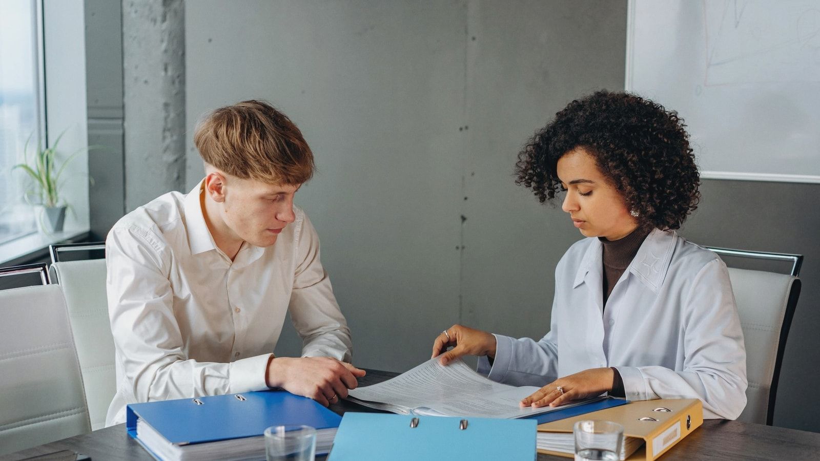Two colleagues discussing important business documents at an office desk.