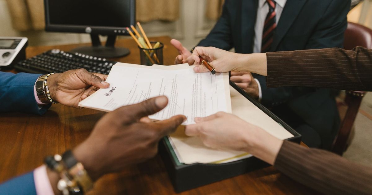 Professional meeting with individuals signing legal documents in an office setting.