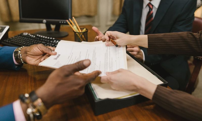 Professional meeting with individuals signing legal documents in an office setting.