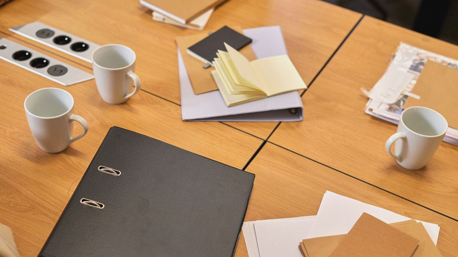 A neat office desk with binders, papers, and coffee mugs arranged neatly, offering a professional workspace vibe.