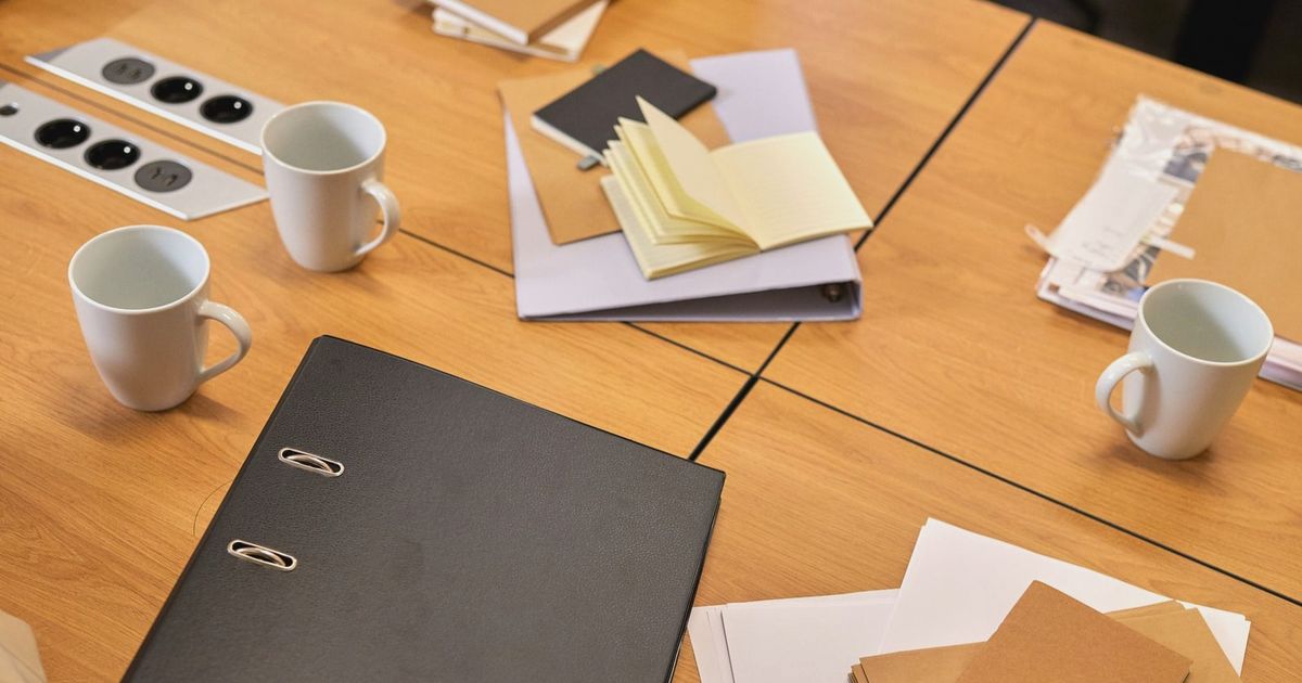 A neat office desk with binders, papers, and coffee mugs arranged neatly, offering a professional workspace vibe.