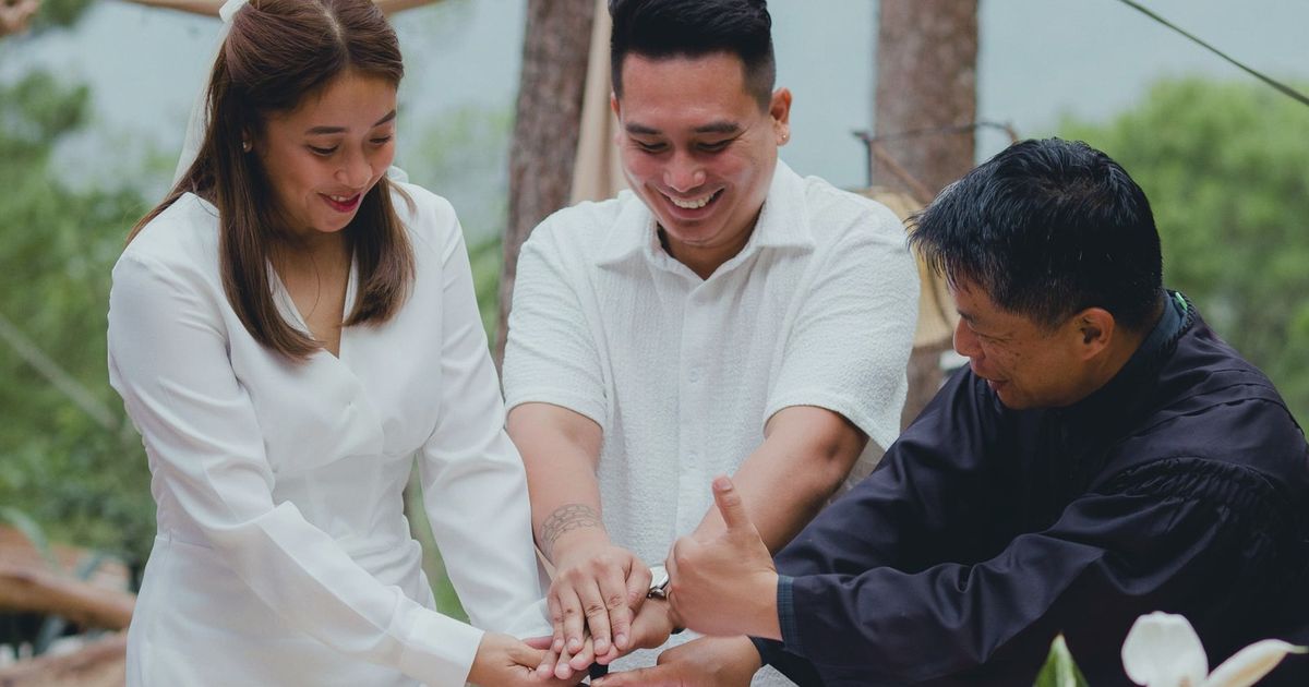 A joyful couple finalizing their wedding with the officiant outdoors.