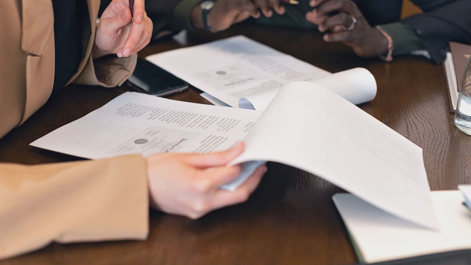 Close-up of professionals reviewing documents during a business meeting in an office setting.
