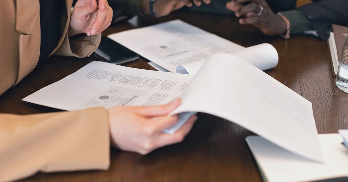 Close-up of professionals reviewing documents during a business meeting in an office setting.