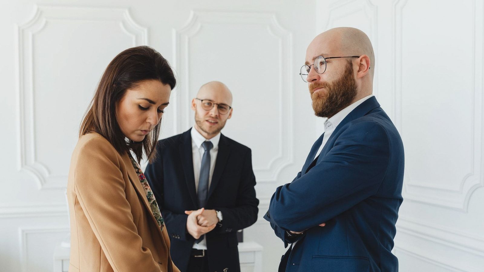 Lawyers discussing case indoors with clients in formal office attire.