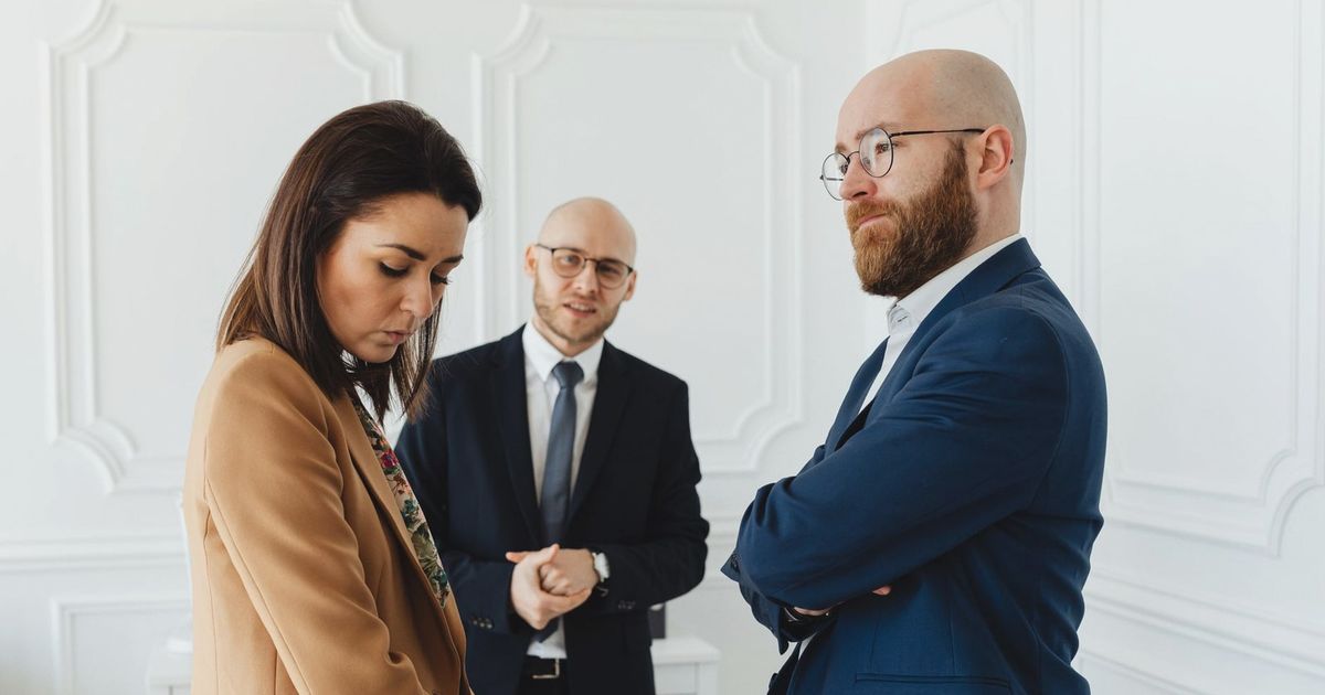 Lawyers discussing case indoors with clients in formal office attire.