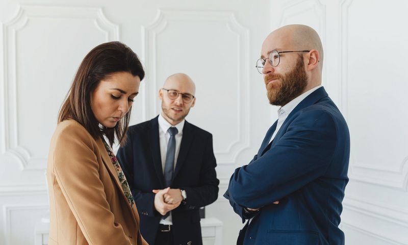 Lawyers discussing case indoors with clients in formal office attire.
