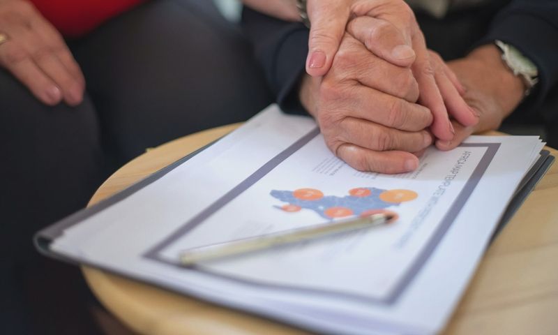 Two adults holding hands over business documents, symbolizing support and partnership.