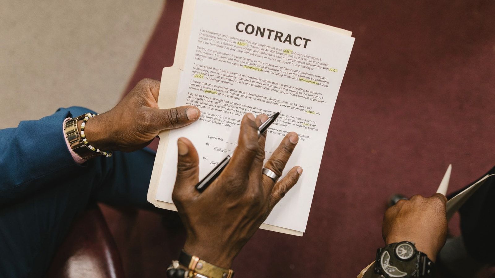 Two businessmen reviewing and signing a contract document in an office setting.