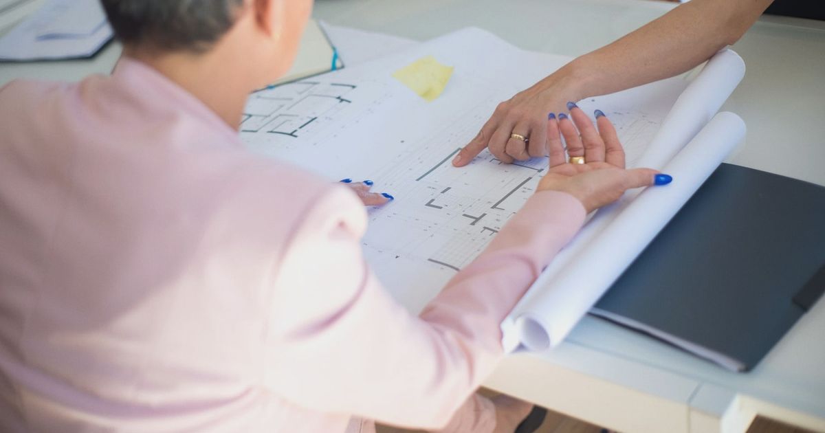 Group discussing architectural floor plans in an office setting.