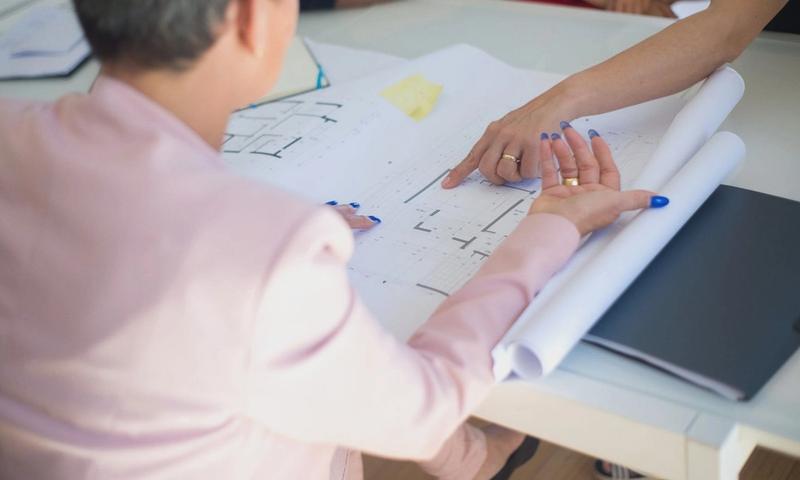 Group discussing architectural floor plans in an office setting.