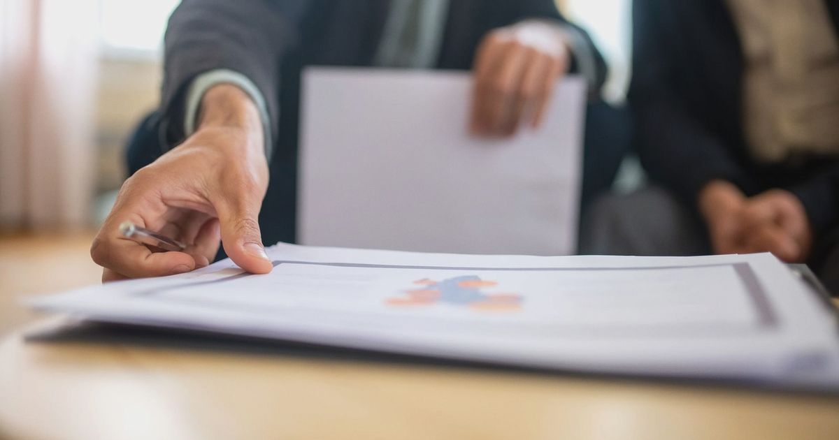 Close-up of a businessman reviewing important documents at a desk in an office setting.