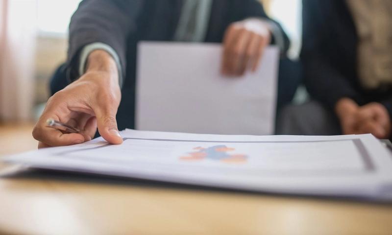 Close-up of a businessman reviewing important documents at a desk in an office setting.