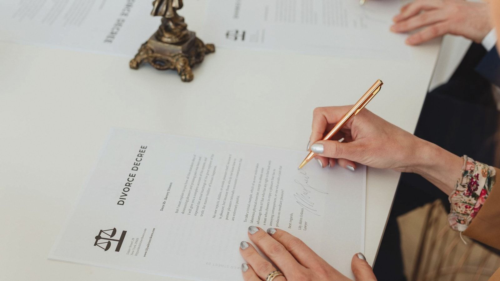 Close-up of hands signing a divorce decree document on a desk, showcasing legal process.