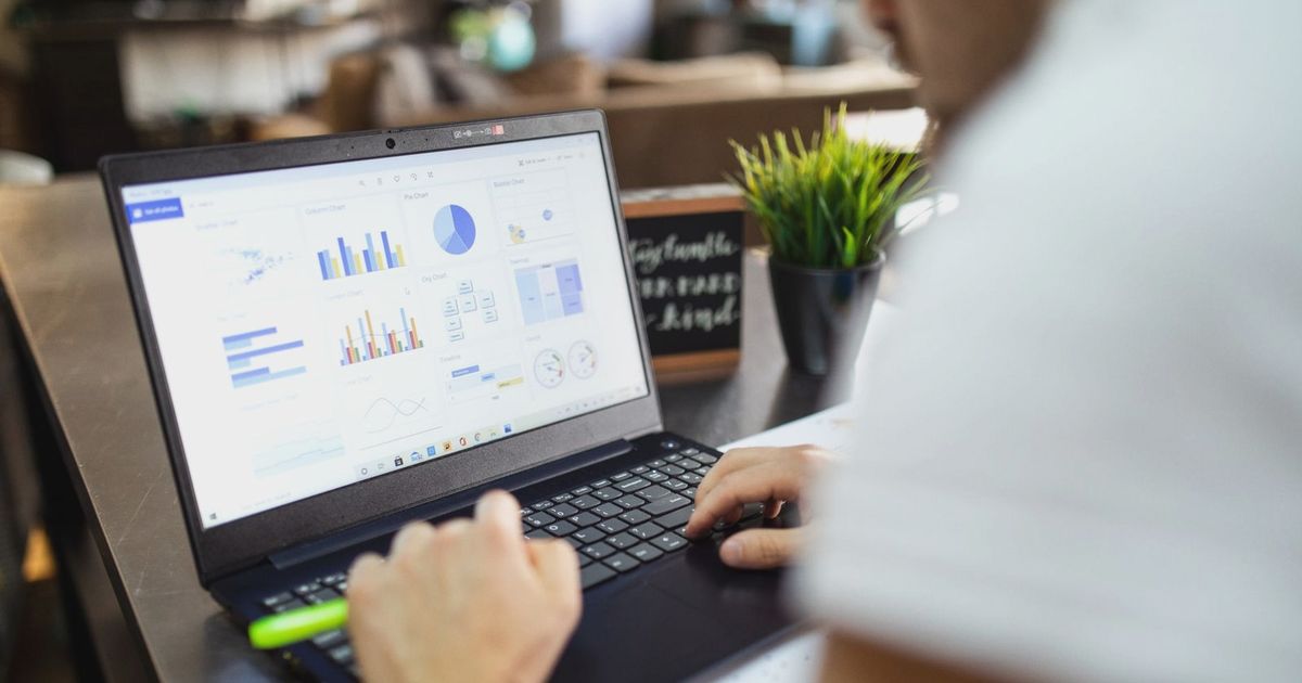 Focused business analysis with charts and graphs on a laptop in a modern office setting.