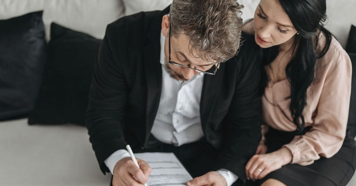 An adult couple sitting together reviewing documents in a modern indoor setting.