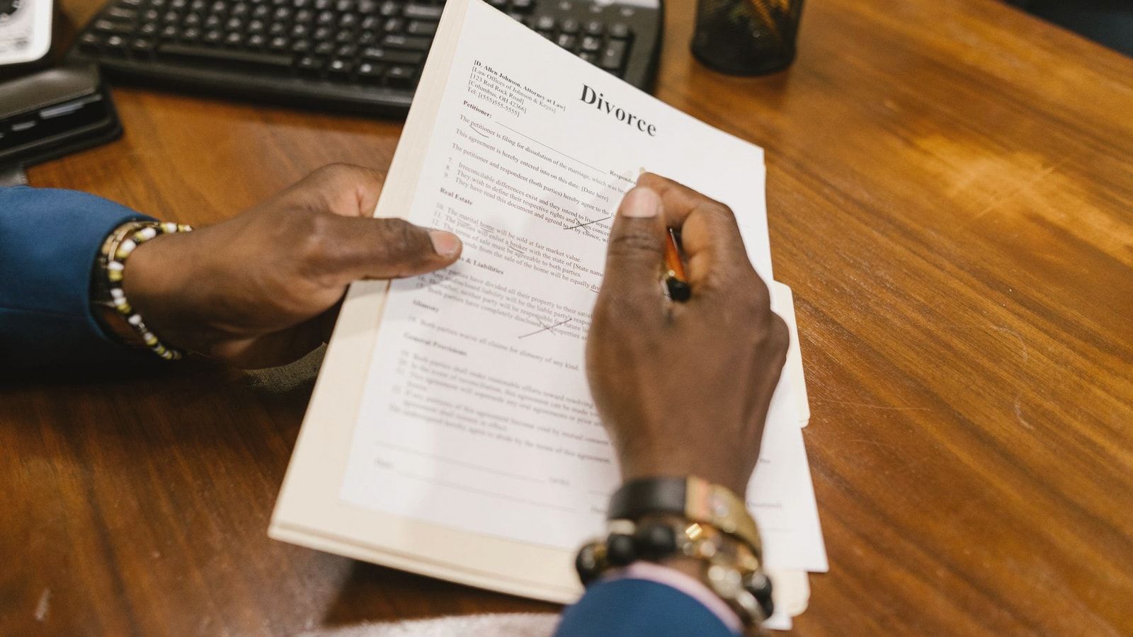 A person signs official divorce documents at an office desk.