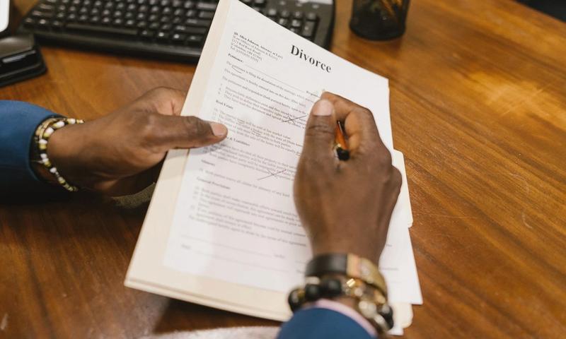 A person signs official divorce documents at an office desk.