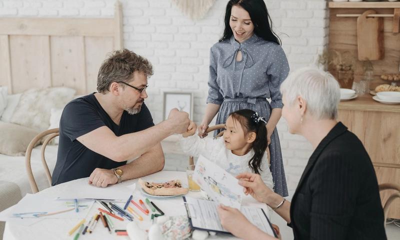 Child with foster parents and a social worker discussing adoption at home.