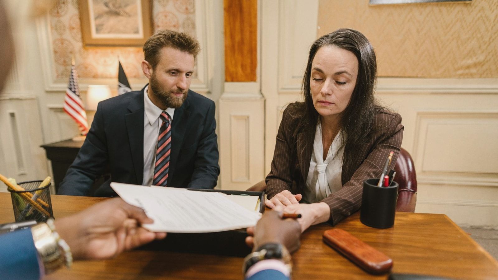 Professional business meeting with a woman and man discussing documents in an office setting.