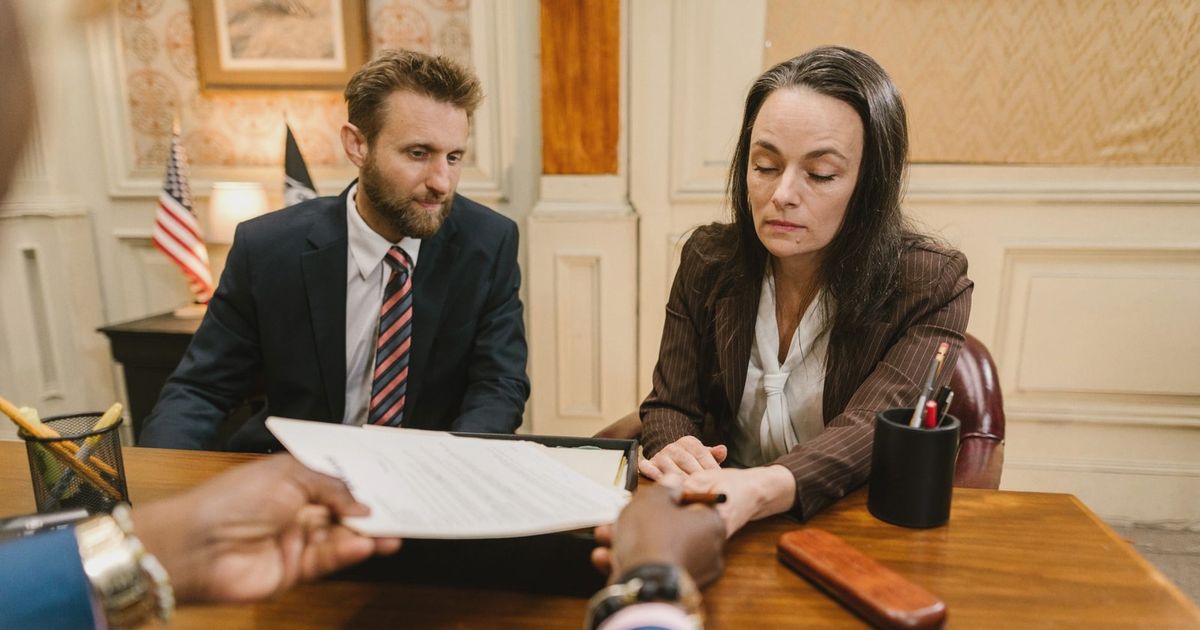 Professional business meeting with a woman and man discussing documents in an office setting.