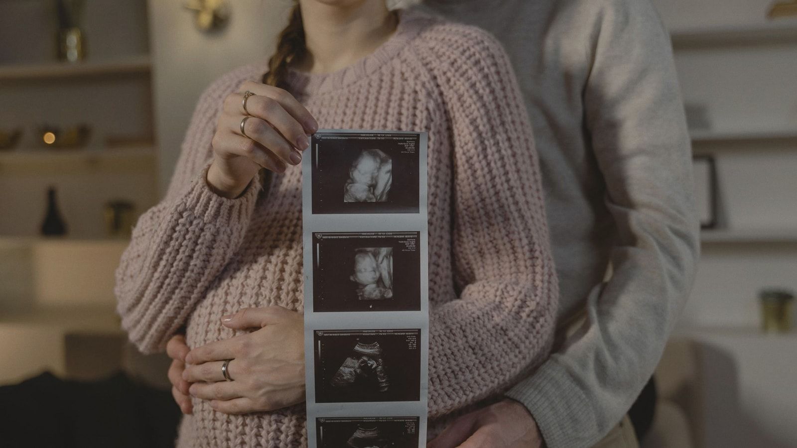 Expectant couple indoors holding ultrasound, symbolizing new life and family bonds.