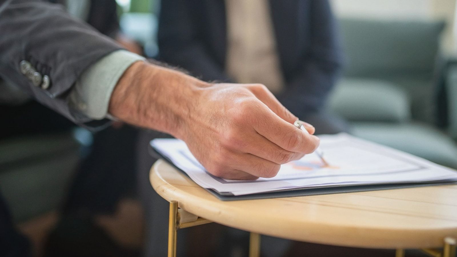 Close-up of a professional during a business meeting, focusing on documents and writing.