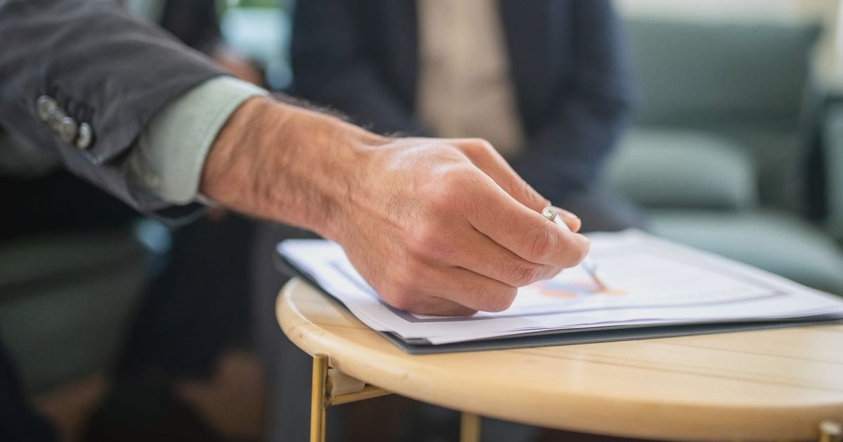 Close-up of a professional during a business meeting, focusing on documents and writing.