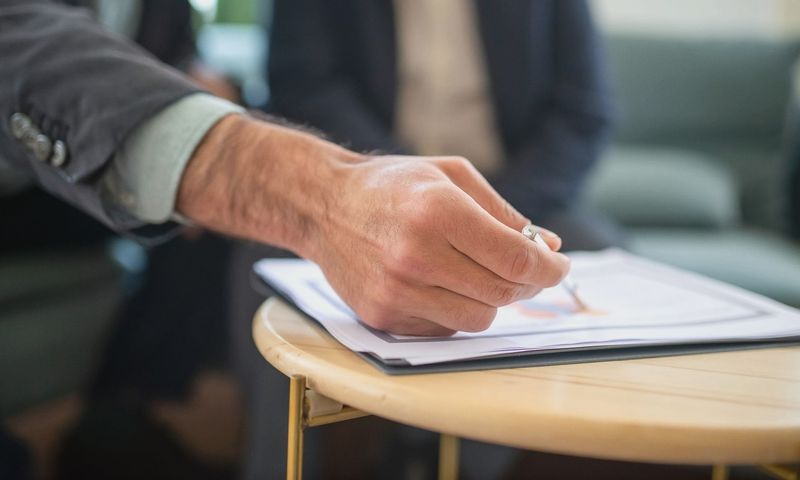 Close-up of a professional during a business meeting, focusing on documents and writing.