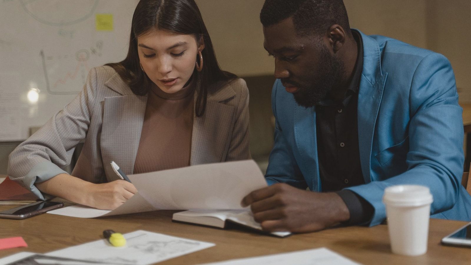 Two colleagues collaborating over documents at an office desk.